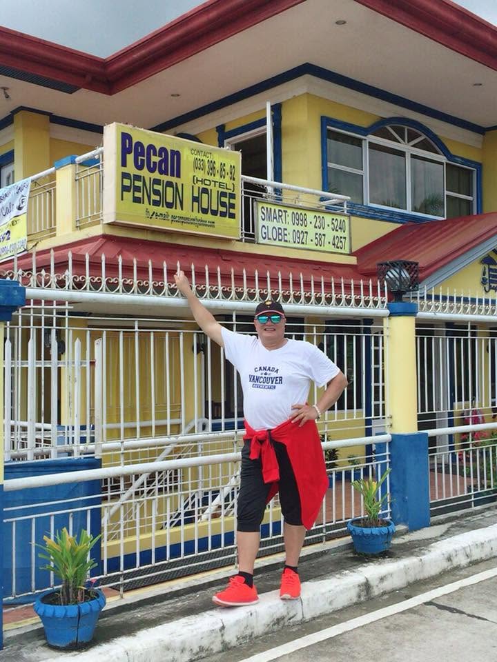 The owner of Pecan Pension House standing outside the property's front gate