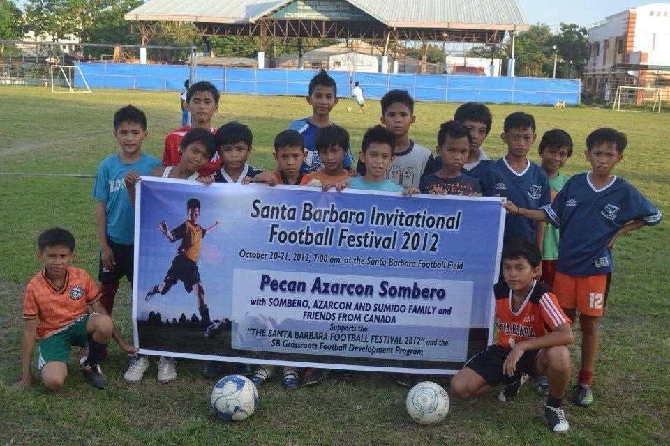Youth football team holding the Santa Barbara Invitational Football Festival banner on a grass field